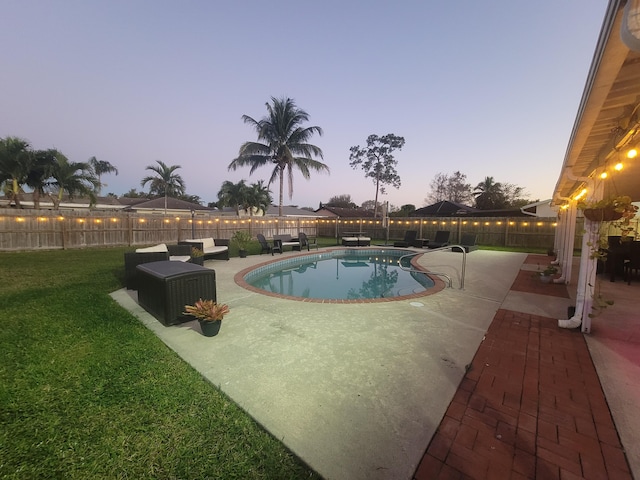 pool at dusk with a patio and a lawn