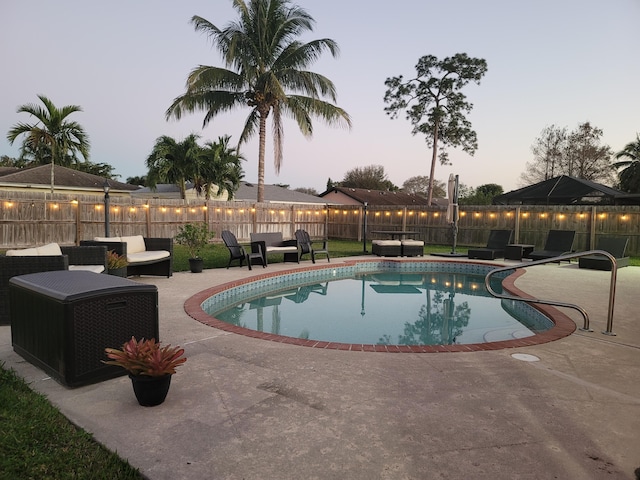 pool at dusk with an outdoor hangout area and a patio