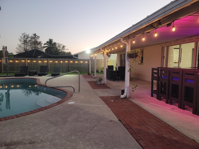 pool at dusk featuring a patio