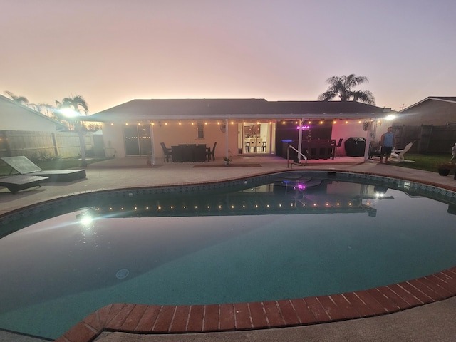 pool at dusk featuring a patio area