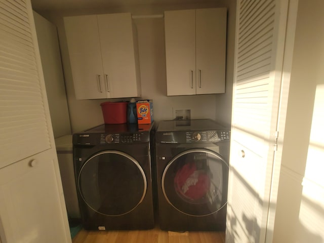 laundry room with cabinets, light hardwood / wood-style floors, and washer and dryer