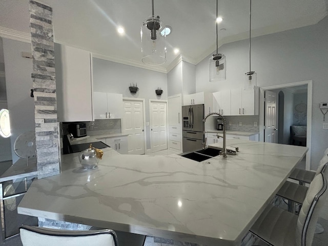 kitchen with stainless steel refrigerator with ice dispenser, tasteful backsplash, high vaulted ceiling, a kitchen breakfast bar, and a peninsula
