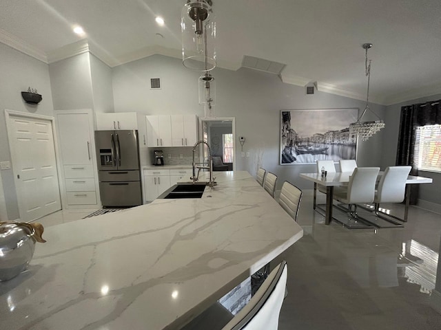 kitchen with stainless steel fridge with ice dispenser, a sink, ornamental molding, white cabinetry, and light stone counters