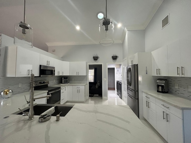 kitchen with appliances with stainless steel finishes, ornamental molding, decorative backsplash, a towering ceiling, and washer / dryer