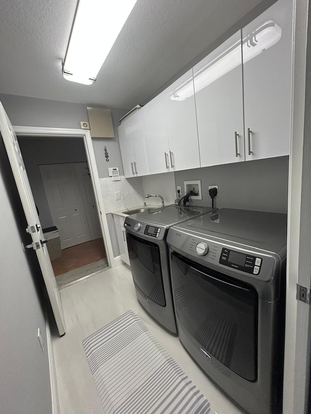 washroom with cabinet space, washing machine and dryer, and a textured ceiling