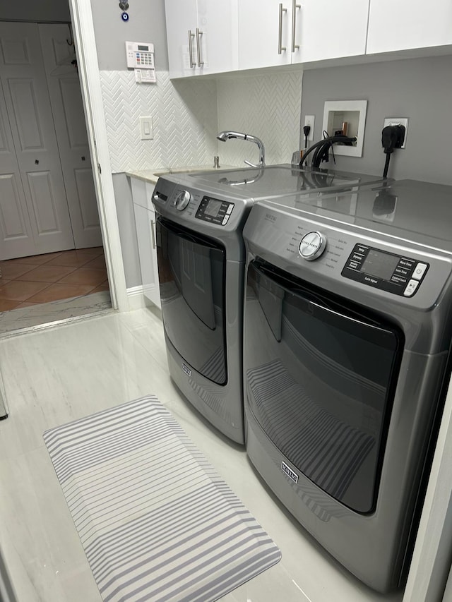clothes washing area featuring cabinet space and washing machine and dryer