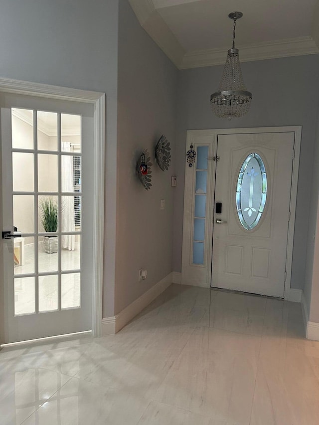 foyer featuring a chandelier, baseboards, marble look tiles, and ornamental molding