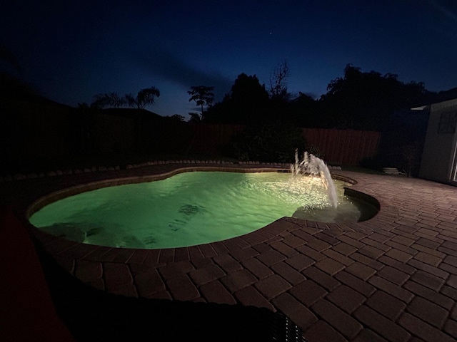 pool at twilight with a patio area and a fenced backyard