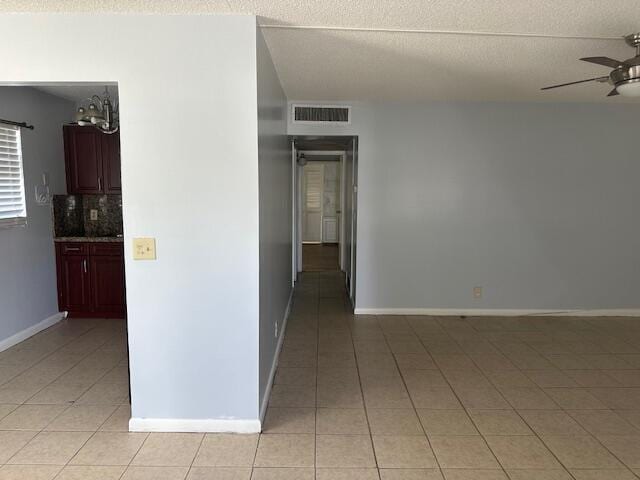 corridor with a textured ceiling and light tile patterned floors