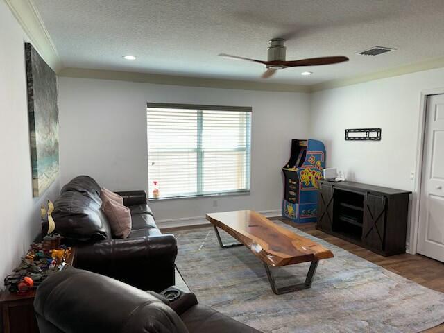 living room with ceiling fan, wood-type flooring, and a textured ceiling