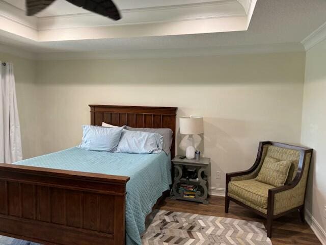 bedroom with crown molding, hardwood / wood-style flooring, and a raised ceiling