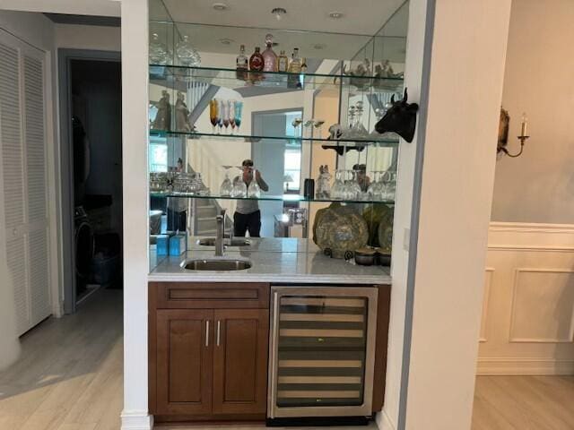 bar featuring beverage cooler, light hardwood / wood-style floors, and sink