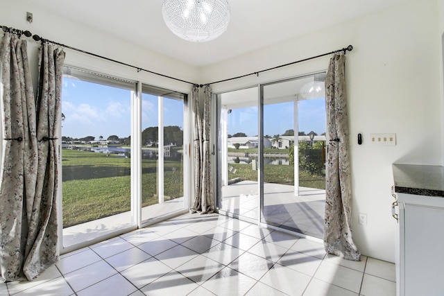 interior space with light tile patterned floors, plenty of natural light, a chandelier, and a water view