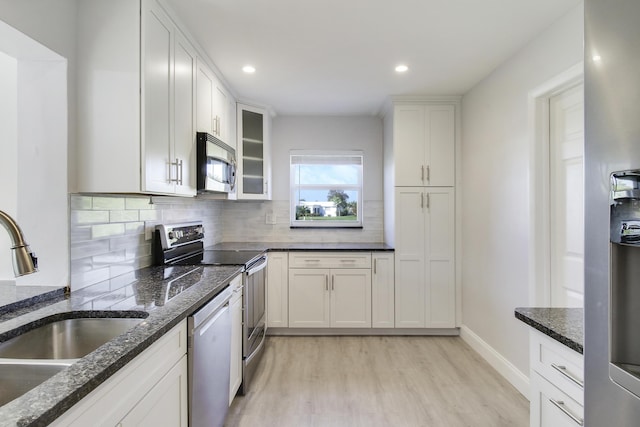 kitchen with sink, stainless steel appliances, dark stone counters, and white cabinets