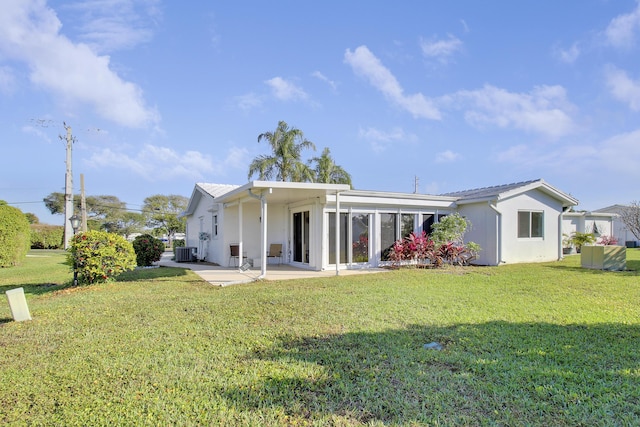 rear view of house with central AC, a patio, and a lawn