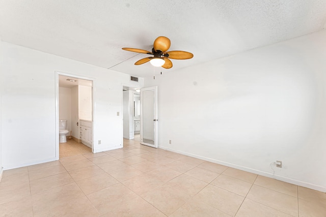 unfurnished bedroom featuring light tile patterned floors, a textured ceiling, and ensuite bathroom