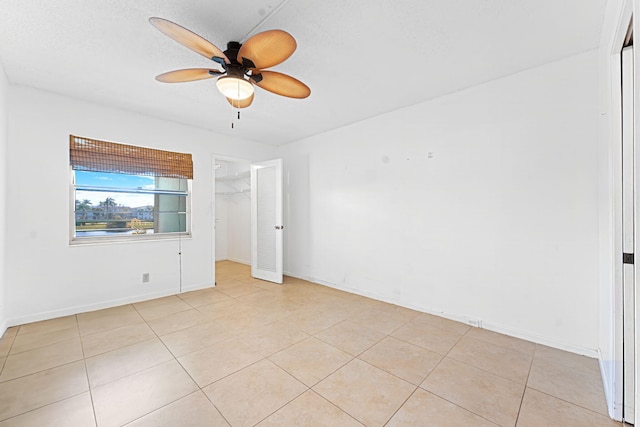 tiled empty room featuring ceiling fan and a textured ceiling