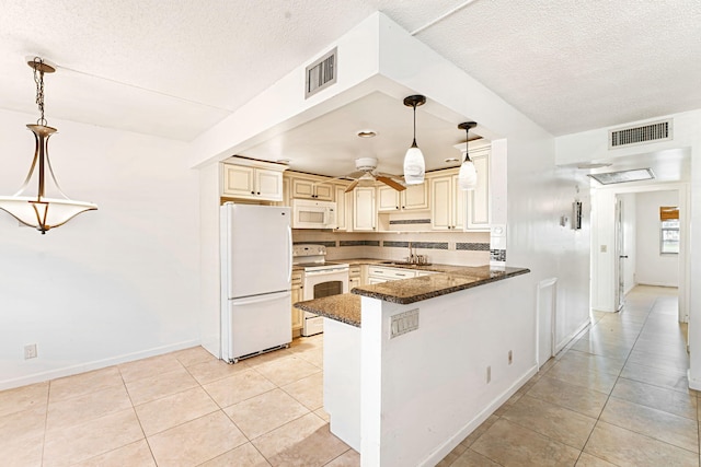 kitchen with light tile patterned flooring, kitchen peninsula, pendant lighting, white appliances, and dark stone counters