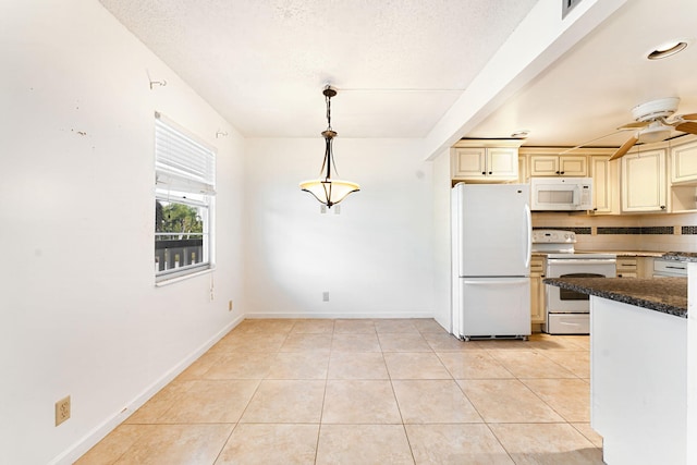 kitchen featuring white appliances, light tile patterned floors, hanging light fixtures, and cream cabinetry