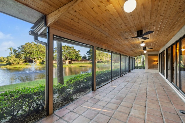 unfurnished sunroom featuring ceiling fan, a water view, and wood ceiling