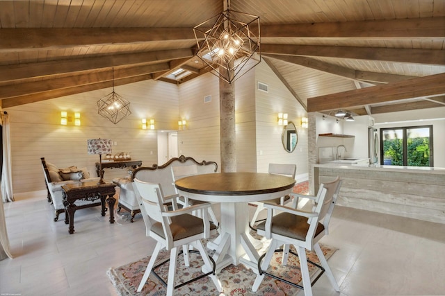 dining area with beam ceiling, sink, wooden walls, and an inviting chandelier