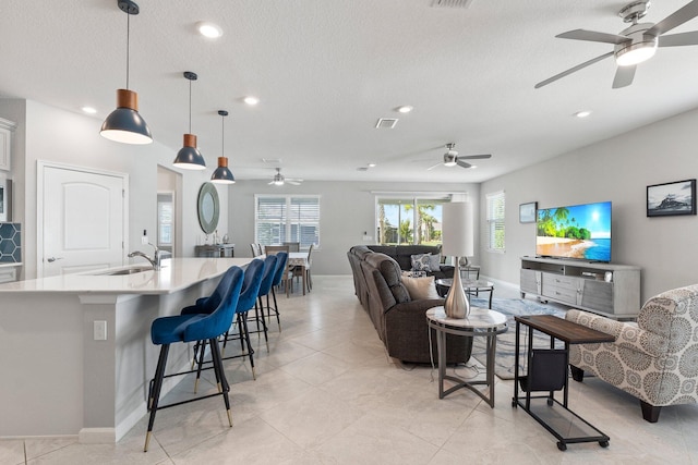 living room featuring light tile patterned flooring, sink, and a textured ceiling