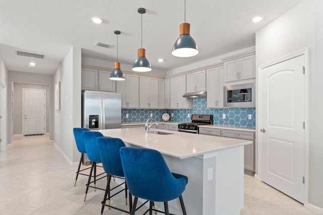 kitchen featuring a breakfast bar, pendant lighting, sink, a kitchen island with sink, and stainless steel appliances