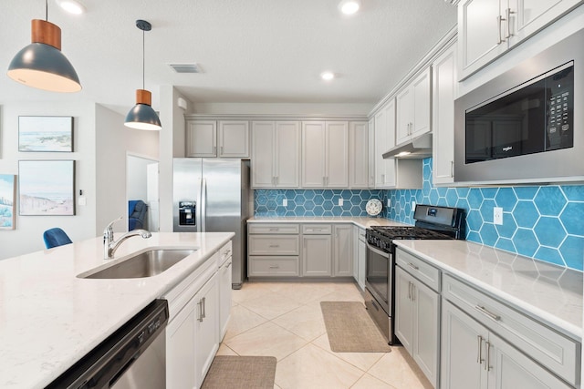 kitchen featuring decorative light fixtures, sink, backsplash, light stone counters, and stainless steel appliances