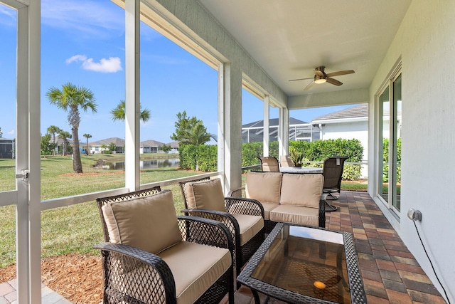 sunroom / solarium with ceiling fan and a water view