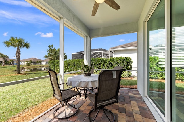 sunroom / solarium with a water view and ceiling fan