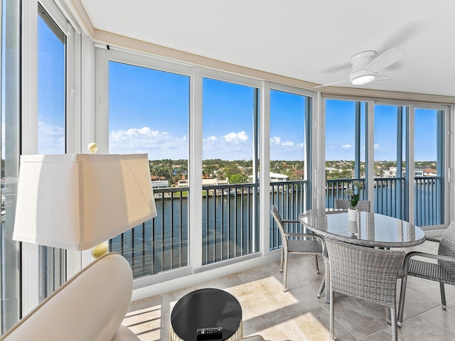 sunroom / solarium featuring a water view and ceiling fan