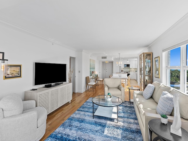 living room featuring a notable chandelier, ornamental molding, and hardwood / wood-style floors