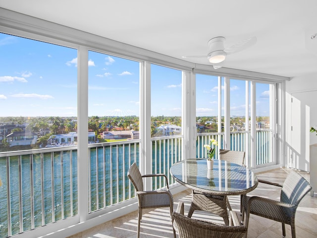 sunroom / solarium with ceiling fan and a water view