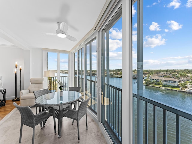 sunroom featuring a water view and ceiling fan