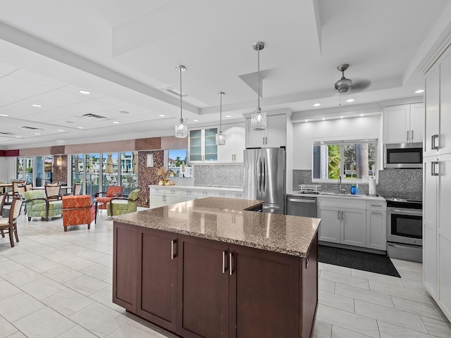 kitchen with white cabinetry, a raised ceiling, stainless steel appliances, and decorative light fixtures