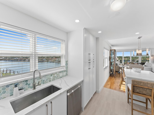 kitchen featuring stainless steel dishwasher, a water view, sink, and white cabinets