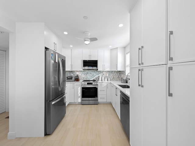 kitchen featuring appliances with stainless steel finishes, sink, tasteful backsplash, and white cabinetry