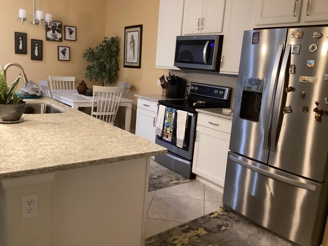 kitchen featuring white cabinetry, sink, a chandelier, light tile patterned floors, and stainless steel appliances