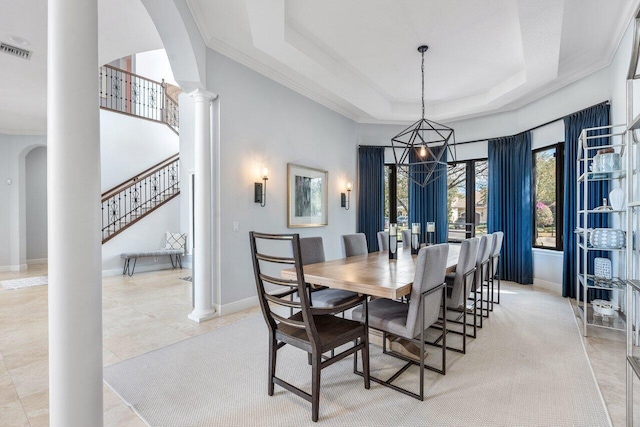 tiled dining room with decorative columns and a tray ceiling