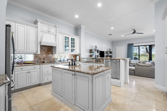 kitchen with dark stone countertops, kitchen peninsula, a kitchen island, and white cabinets