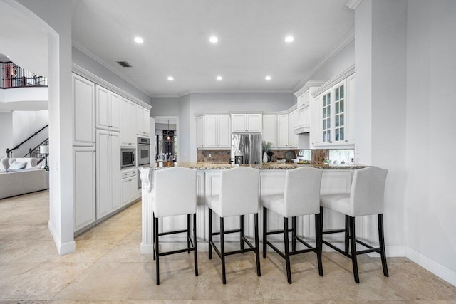 kitchen with stainless steel appliances, tasteful backsplash, white cabinets, a kitchen bar, and kitchen peninsula