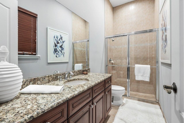 bathroom with vanity, a shower with shower door, tile patterned floors, and toilet