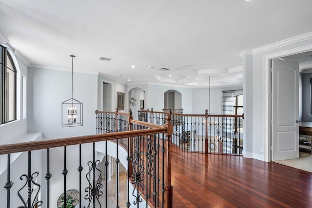 corridor featuring ornamental molding, hardwood / wood-style floors, a notable chandelier, and a textured ceiling