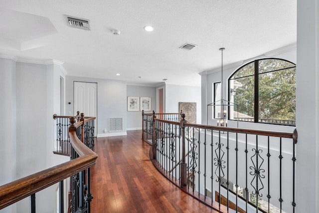 hall featuring ornamental molding, dark wood-type flooring, a textured ceiling, and a chandelier