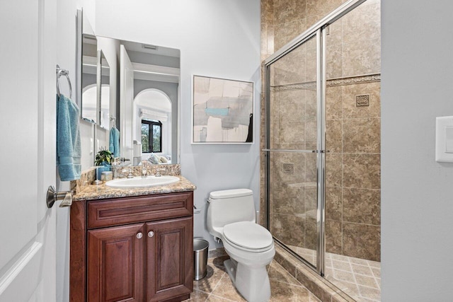 bathroom with tile patterned floors, vanity, toilet, and a shower with shower door