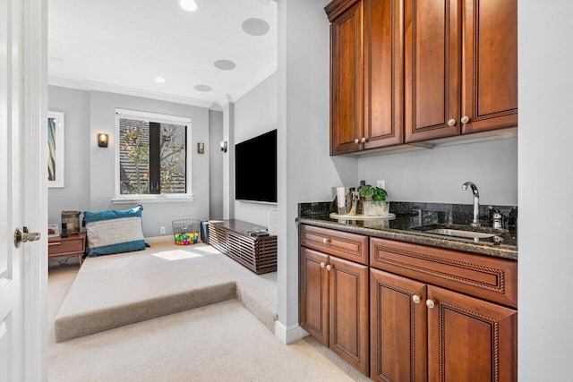 interior space featuring dark stone countertops, sink, crown molding, and light colored carpet