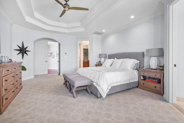 carpeted bedroom with ensuite bathroom, ceiling fan, ornamental molding, and a raised ceiling