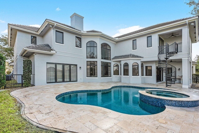 rear view of property with a swimming pool with hot tub, a balcony, ceiling fan, and a patio area