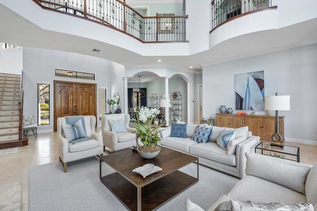 living room featuring crown molding, a towering ceiling, and ornate columns