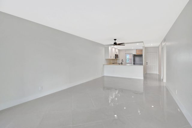 unfurnished living room with sink and ceiling fan